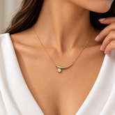 Gold Curved Bar Pendant Necklace Round Crystal Six Prong - pendant macro on cream satin: detailed elevated view of curved gold bar showing mirror-polish warm gold arc surface with smooth tapered horn form, round brilliant white crystal zirconia in six-prong gold setting at thick left end with full stone and prong detail visible, bar tapering to sharp right point