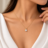 Round Solitaire Crystal Pendant Necklace Gold Four Prong S925 - pendant macro front on cream satin: front-facing close view of large round brilliant white crystal zirconia solitaire showing full brilliant-cut facet arrangement and colourless white brilliance, four warm gold prongs at compass points of stone girdle, rectangular bail with two crystal accents above, fine gold chain