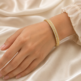 Gold-plated stainless steel bangle bracelet with clear stones worn on a wrist