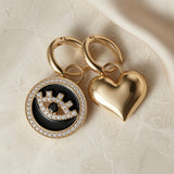 Heart & Evil Eye Mismatched Hoop Earrings - both charms flat lay on marble with silk