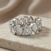 Larme Pear Crystal Eternity Ring - front elevated view on marble with silk backdrop showing pear crystal brilliance
