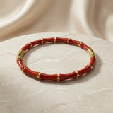 Rouge Bamboo Enamel Bangle - elevated angled view on marble pedestal with silk backdrop