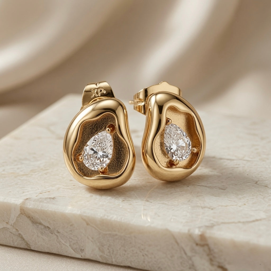 Molten Pear Crystal Stud Earrings - pair angled view showing pear crystal in sand-textured gold crater on marble