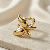 Fleur Gold Bloom Ring - front three-quarter view on marble with silk showing four-petal bloom and open back