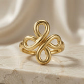 Infinity Bloom Gold Ring - front view on marble showing double infinity cross four-petal motif