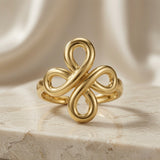 Infinity Bloom Gold Ring - front view on marble showing double infinity cross four-petal motif