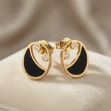 Lunaire Noir Crystal Stud Earrings - pair on sand surface showing full circular disc profile and butterfly backs