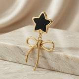 Étoile Noir Bow Drop Earrings - single earring macro on marble with silk showing black star stud, jump ring link and wire bow knot detail