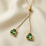Émeraude Coeur Lariat Necklace - macro on ivory silk showing faceted emerald crystal heart detail, gold bezel and bead slider