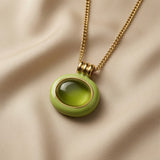 Pistache Cabochon Pendant Necklace - macro on silk showing coiled gold spring bail, inner gold bezel and cabochon crystal depth