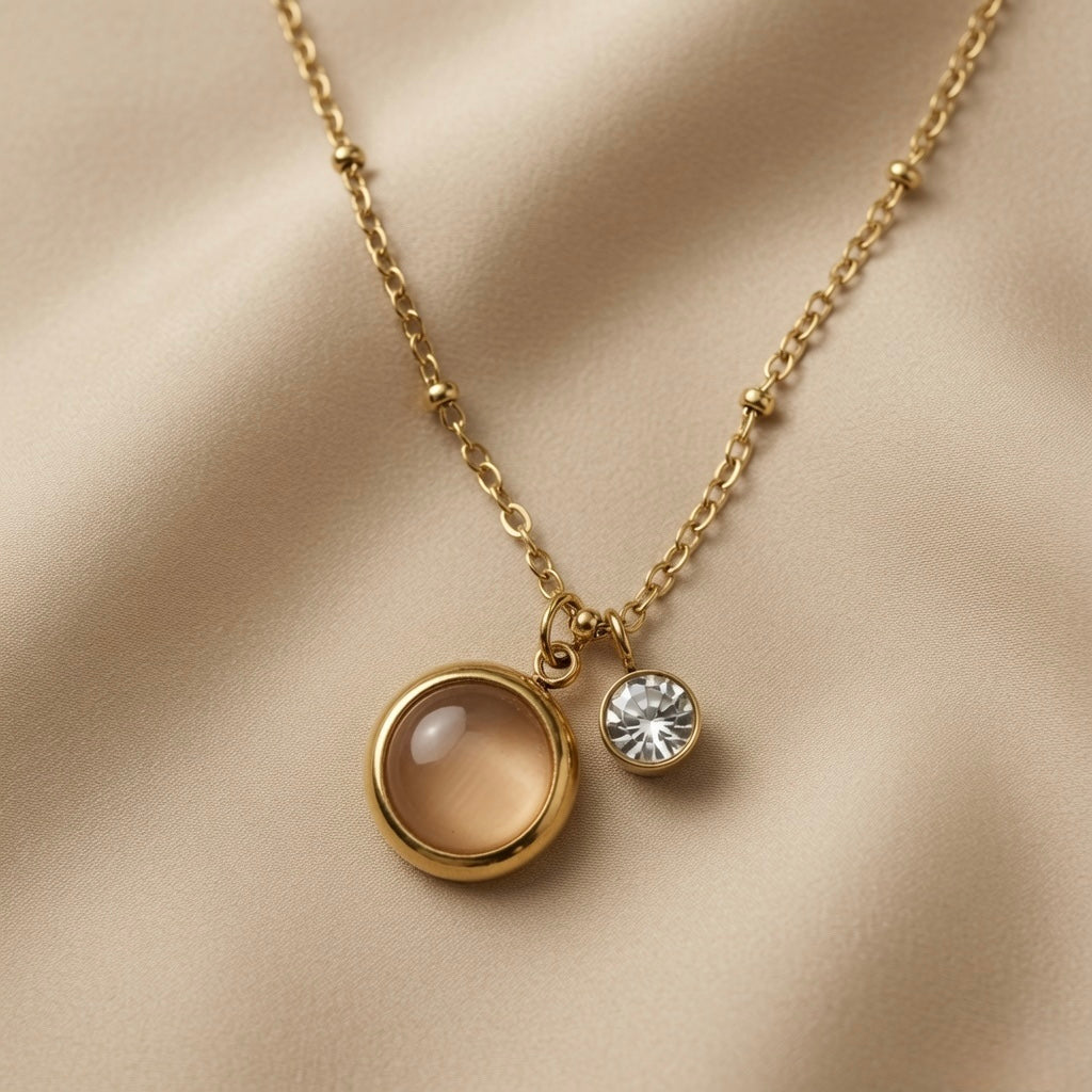 Lune Dorée Crystal Duo Pendant Necklace - macro close-up on champagne silk showing large warm champagne moonstone cabochon in deep gold bezel beside small brilliant crystal zirconia pendant on satellite chain