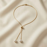 Perle Bolo Lariat Necklace - full flat lay on ivory silk showing complete round snake chain, lobster clasp extender, gold bolo slider and two pearl drops