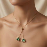 Émeraude Coeur Lariat Necklace - worn on model décolletage showing two emerald hearts resting below collarbone on gold snake chain