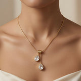 Duo Larme Crystal Asymmetric Pendant Necklace - worn on model collarbone against white silk dress showing upper white crystal pear at collarbone and lower pear at sternum, white fire against warm skin