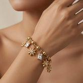Soleil Baguette Fringe Charm Set bracelet - worn on model wrist and collarbone showing five-charm alternating fringe of three gold sunflowers and two baguette crystal drops swinging freely on ball and barrel station snake chain against warm skin