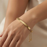 Lover Dream Curved Bar Bolo Bracelet - worn on model wrist showing curved gold bar lying flat against inner wrist with LOVER DREAM inscription reading against warm skin, bolo slider and gold ball tails at back of wrist