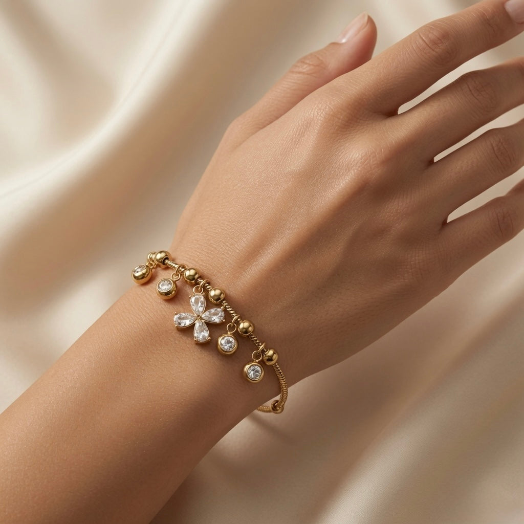 Fleur Cristal Fringe Drop Snake Chain Bracelet - worn on model wrist showing five-drop crystal fringe hanging below wrist: marquise crystal flower at centre, four round crystal drops flanking, all swinging freely on gold ball station snake chain against warm skin