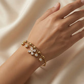 Fleur Cristal Fringe Drop Snake Chain Bracelet - worn on model wrist showing five-drop crystal fringe hanging below wrist: marquise crystal flower at centre, four round crystal drops flanking, all swinging freely on gold ball station snake chain against warm skin