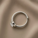 Éclat Wide Band Solitaire Adjustable Ring - side profile on taupe silk showing wide flat-topped mirror-polished band with open-back adjustable gap at base, micro-pavé crystal shoulder accents and round brilliant crystal zirconia solitaire in four-prong setting