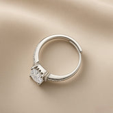 Éclat Wide Band Solitaire Adjustable Ring - overhead view on champagne silk showing wide mirror-polished rhodium-plated band with open-back adjustable mechanism, micro-pavé crystal zirconia shoulder accents and round brilliant crystal zirconia solitaire in four-prong low-profile setting