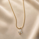 Tulipe Blanche Crystal Bud Pendant Necklace - close-up on champagne silk showing white tulip bud pendant in full detail: pear-cut diamond-clear white crystal zirconia bud in minimal gold bezel set point-downward, two marquise-cut white crystal zirconia leaves set horizontally outward from fine gold stem, smooth gold bail at top, fine twisted gold cable chain above