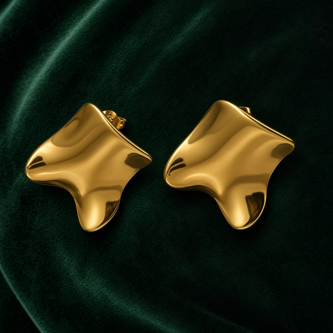 Gold Sculptural Wave Square Stud Earrings - pair face-on on deep forest green velvet showing both earrings side by side: generously proportioned wave-distorted square studs in high mirror-polish 18K gold, deeply warped three-dimensional form with concave hollows and convex peaks, warm gold mirror-polish surface catching light from multiple angles simultaneously