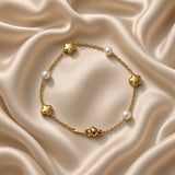 Gold Star and Pearl Station Bracelet Milgrain - circular flat lay on cream satin alternate angle: six-station bracelet in loop showing three puffy gold milgrain star charms and three round white pearl inline stations on fine gold cable chain, lobster clasp with engraved gold bar tag at bottom centre