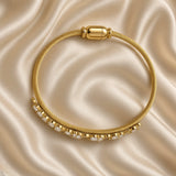 Gold Twisted Wire Bangle Floral Marquise Crystal Garland Magnetic Clasp - angled flat lay on cream satin: three-quarter view of bangle showing twisted rope wire texture detail and full floral crystal garland with marquise navette and round brilliant white crystal stones at varied orientations in warm gold prong settings, capsule magnetic clasp at top, cream satin background