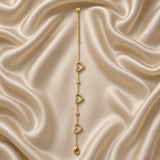 Gold Open Pavé Heart Charm Bracelet Bezel Crystal Station Chain - vertical detail flat lay on cream satin: straight layout showing full heart charm and bezel station sequence in alternating heart-station-heart-station-heart arrangement on fine warm gold cable chain, micro-pavé white crystal detail on each open heart frame visible, cream satin background