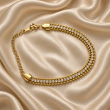 Gold Three Row Bracelet Crystal Tennis Centre Ball Bead Chain Lobster Clasp - overhead circular flat lay on cream satin: full bracelet in circular form showing complete three-row bead-crystal-bead architecture, warm gold tapered shield end caps gathering all three rows, lobster clasp and extension chain at top, cream satin background