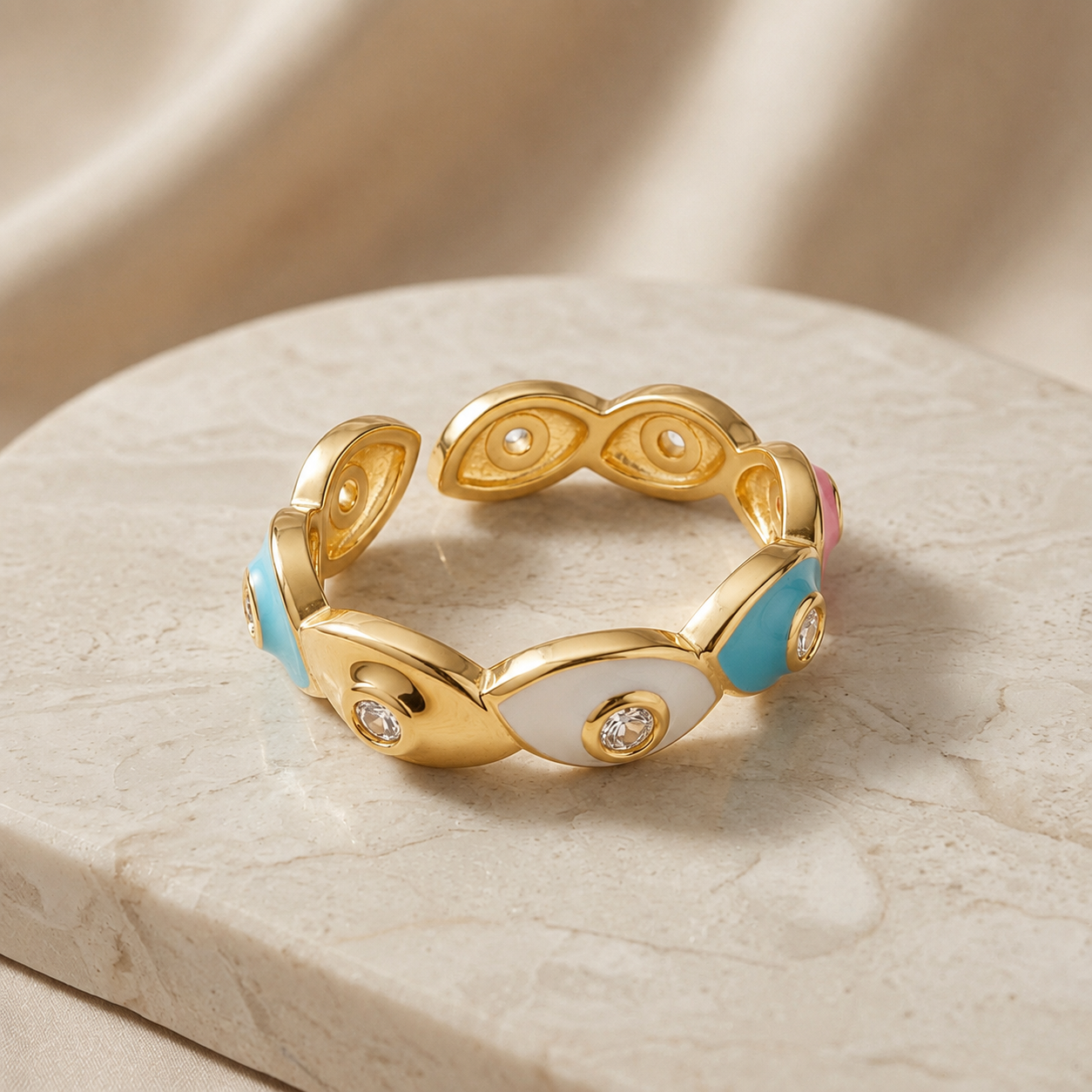 Chromatic Evil Eye Eternity Ring - angled view on marble pedestal showing blue, pink, white and navy enamel eyes with crystal pupils