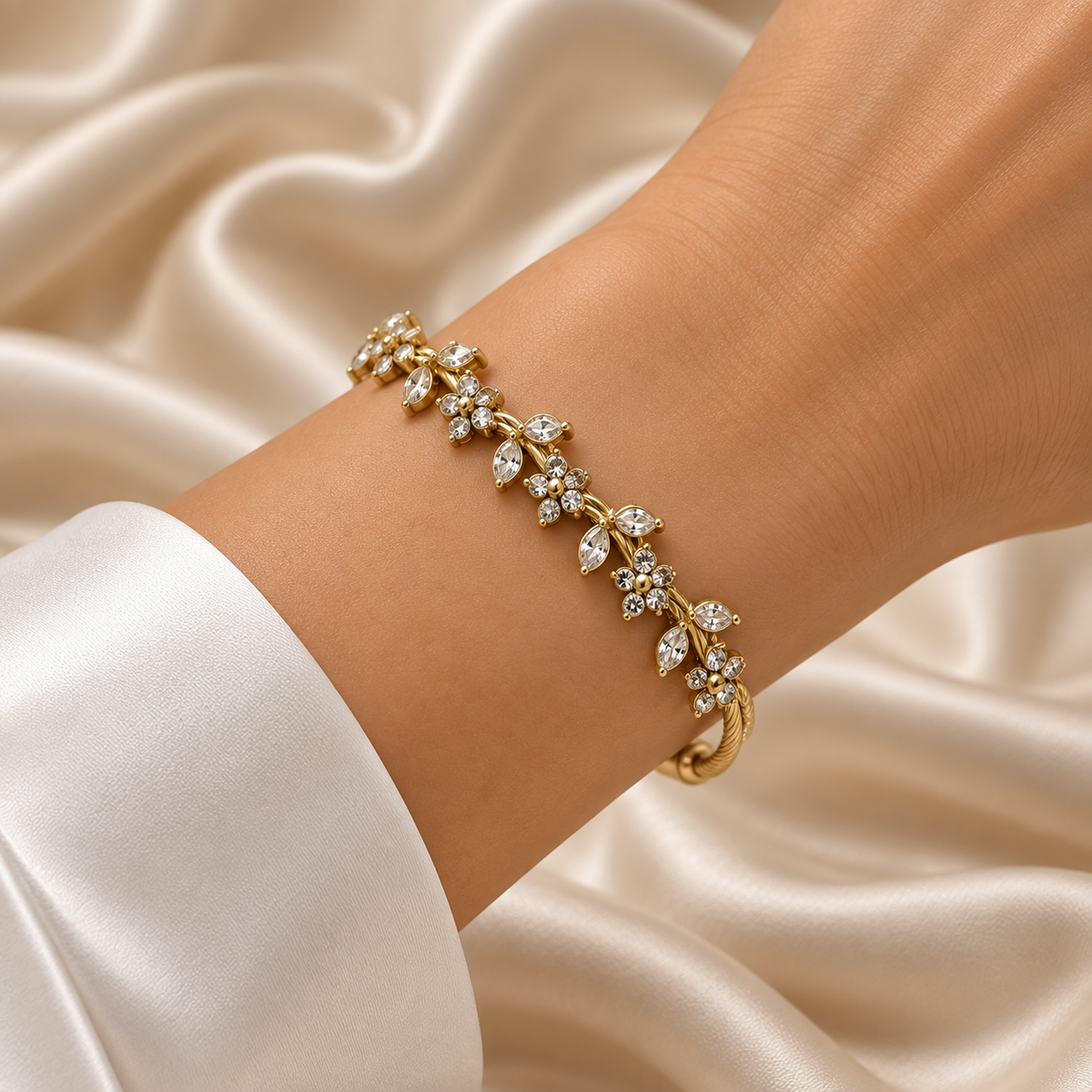 Gold Twisted Wire Bangle Floral Marquise Crystal Garland Magnetic Clasp - hero flat lay on cream satin: full bangle in circular form showing twisted rope wire body in warm 18K gold, continuous floral marquise and round crystal garland across front half in individually prong-set white crystal zirconia, mirror-polish capsule magnetic clasp at top, cream satin background