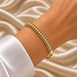 Gold Three Row Bracelet Crystal Tennis Centre Ball Bead Chain Lobster Clasp - hero overhead flat lay on cream satin: full bracelet in circular form showing three-row architecture of upper smooth warm gold ball bead chain row, centre round brilliant white crystal zirconia tennis row, lower smooth warm gold ball bead chain row, tapered shield end caps, lobster clasp and adjustable curb link extension chain with flat tag, cream satin background