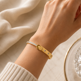 Gold-tone crystal accent bangle bracelet worn on a wrist with a row of clear square accents