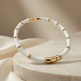 Blanc Bamboo Enamel Bangle - elevated view on stone pedestal with soft backdrop