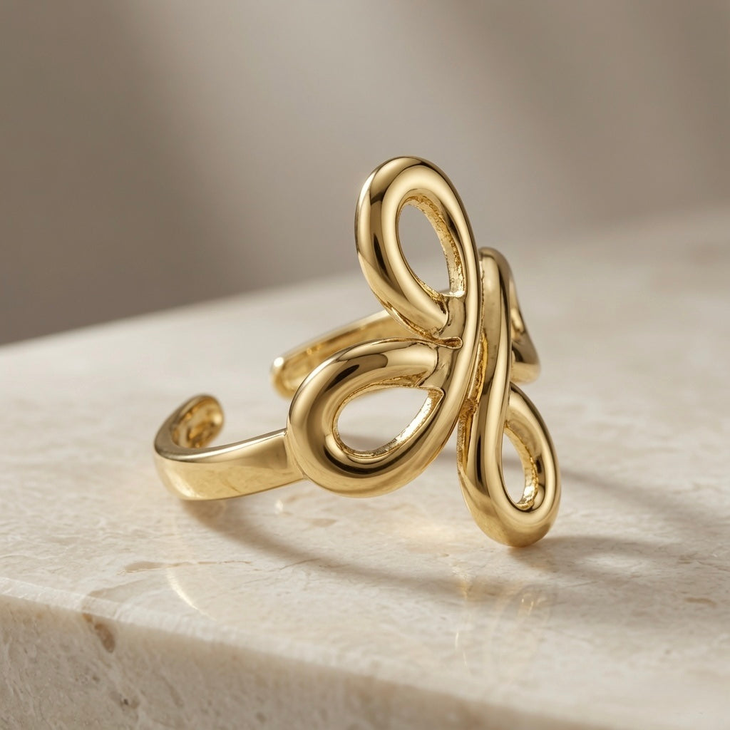 Infinity Bloom Gold Ring - angled three-quarter view on travertine showing full sculptural form and mirror polish