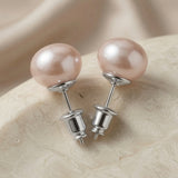 Perle Blush Pearl Stud Earrings Silver - pair on travertine showing blush pearl and silver cup setting and screw-back detail
