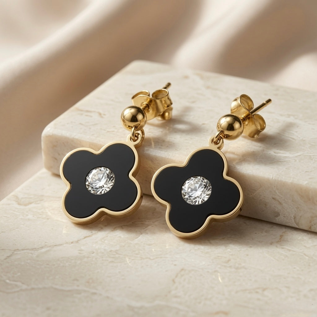Noir Fleur Crystal Drop Earrings - pair on marble block with silk backdrop showing full drop length and gold border detail