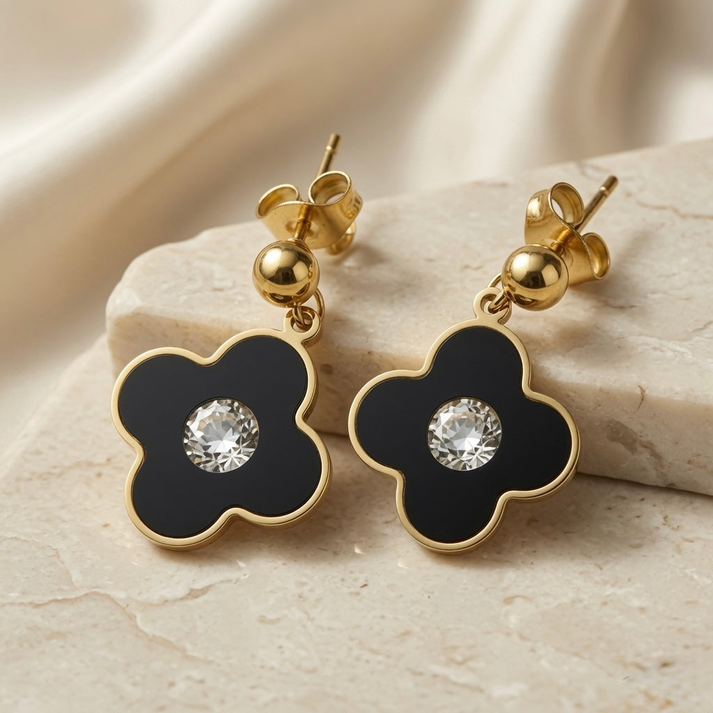 Noir Fleur Crystal Drop Earrings - pair on marble block showing black enamel petals and brilliant crystal zirconia centre