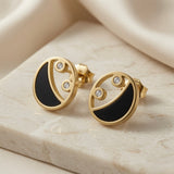 Lunaire Noir Crystal Stud Earrings - pair on marble showing black enamel crescent and twin crystal zirconia in gold disc