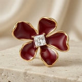 Vigne Crystal Fleur Stud Earrings - single earring macro on travertine showing princess-cut zirconia in four-prong gold setting and petal detail