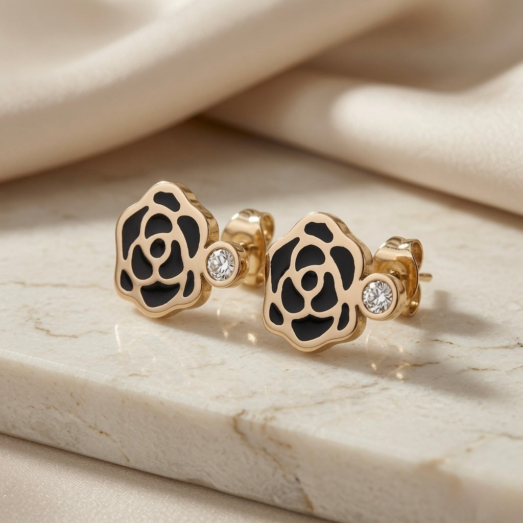 Camélia Noir Crystal Earrings - black enamel stud style pair on marble with silk showing camellia rose and side crystal accent