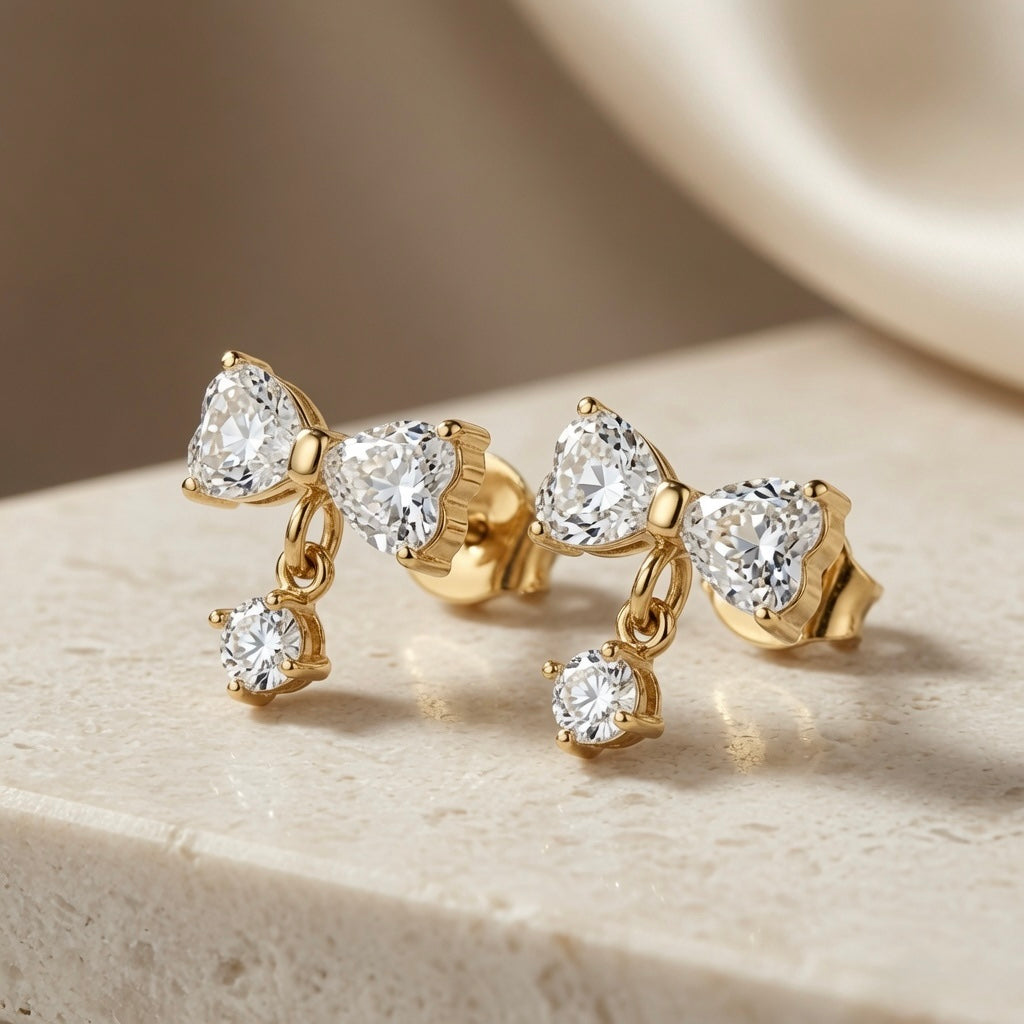 Noeud Crystal Bow Drop Earrings - pair side angle on travertine showing bow silhouette, gold link and drop length