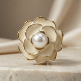 Camélia Blanc Pearl Stud Earrings - single earring macro on travertine with silk showing layered petal detail, gold borders and pearl