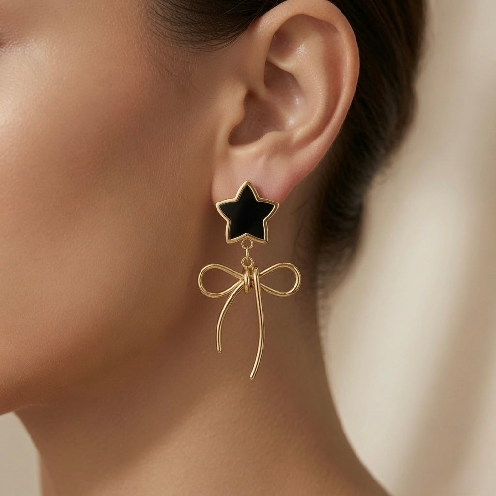 Étoile Noir Bow Drop Earrings - worn on model ear showing star at lobe and gold wire bow drop below jaw