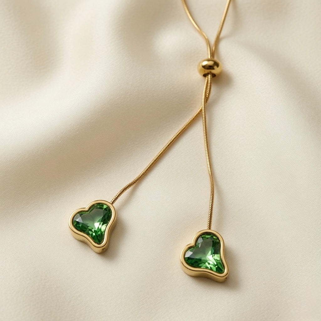 Émeraude Coeur Lariat Necklace - macro on ivory silk showing faceted emerald crystal heart detail, gold bezel and bead slider