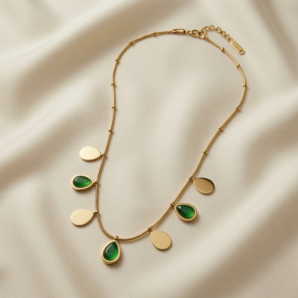 Pluie Verte Charm Necklace Gold & Emerald - full necklace flat lay on silk showing lobster clasp, extender chain and full charm arc