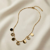 Sept Lunes Disc Station Necklace - full flat lay on ivory silk showing complete satellite chain with lobster clasp, curb extender and all seven alternating gold disc and moonstone circle pendants