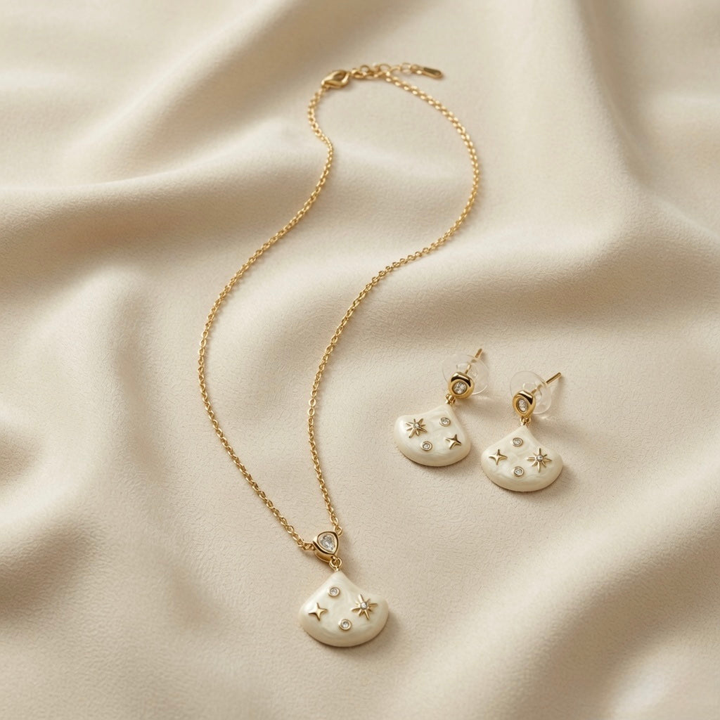 Constellation Ivoire Jewellery Set - flat lay on ivory silk showing necklace and earring pair with ivory enamel fan pendants and star motifs