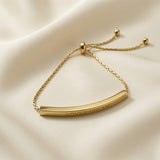 Lover Dream Curved Bar Bolo Bracelet - close-up flat lay on ivory silk showing LOVER DREAM engraving on curved gold bar face, bolo slider mechanism and cable chain detail